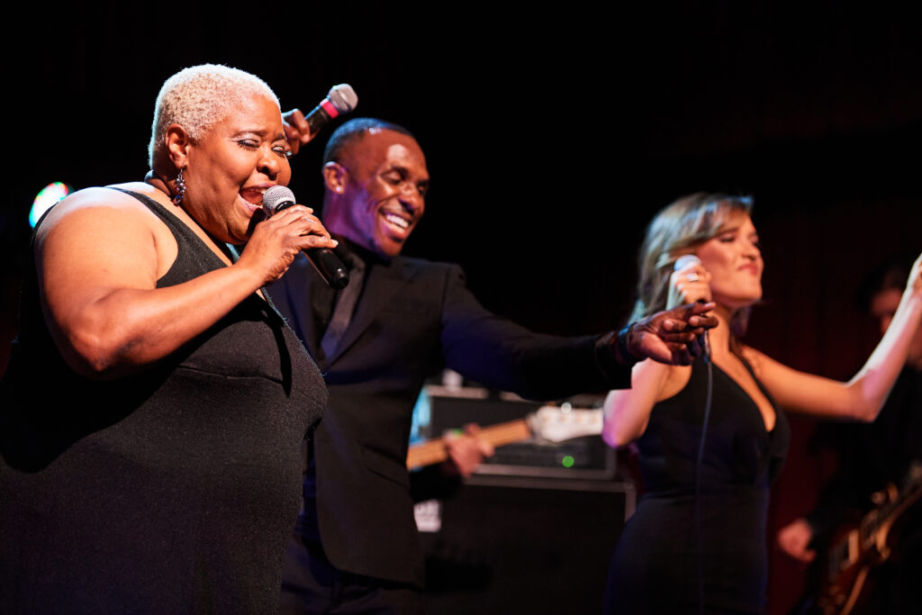 The front line of Elevation singing and dancing at a showcase event