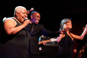 The front line of Elevation singing and dancing at a showcase event 