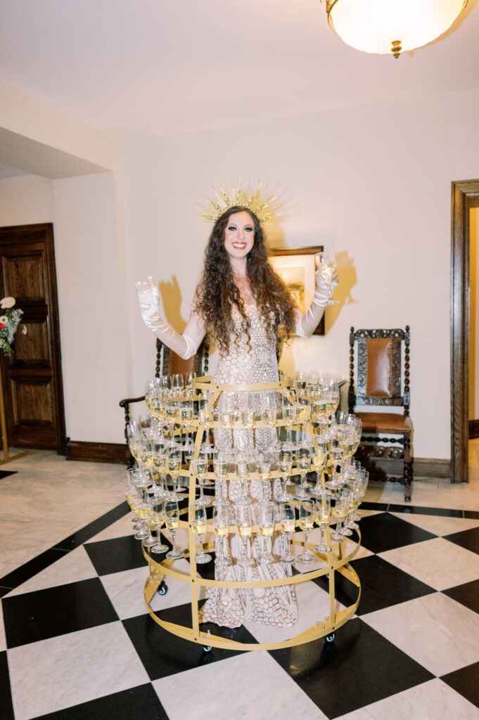 BVTLive! Champagne skirt greeter greeting guests at thee entryway of the event with cold fresh glasses of champagne from her skirt apparatus by Haley Richter Photography