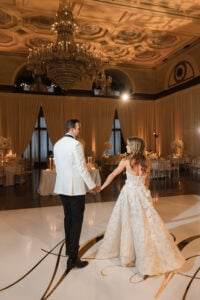 Bride and groom holding hands on dancefloor