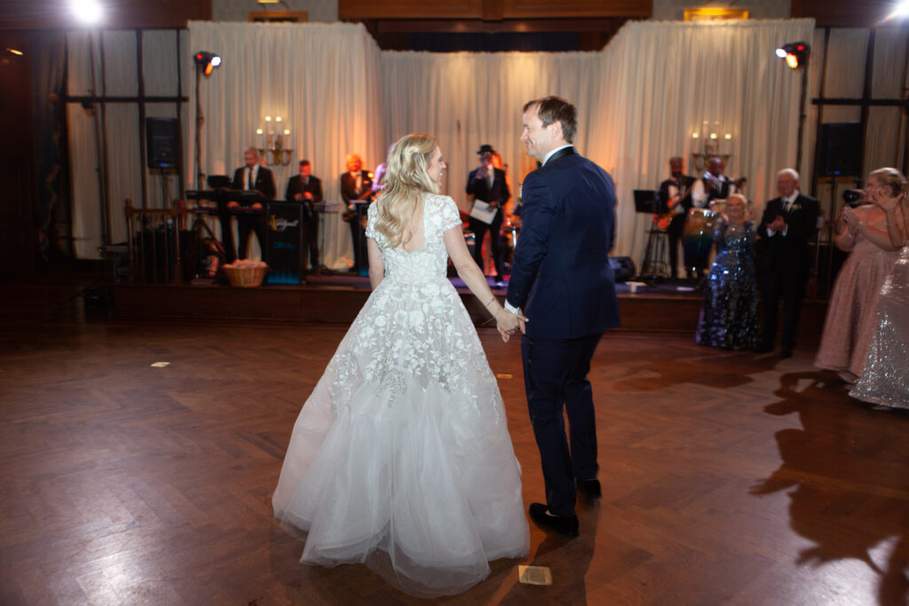 Bride and groom walking to take the dance floor for their first dance at wedding reception.