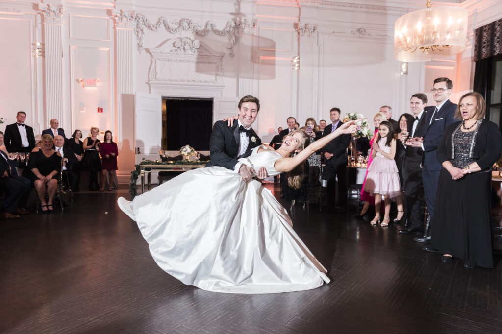 Groom dips his bride on the dance floor during their wedding reception